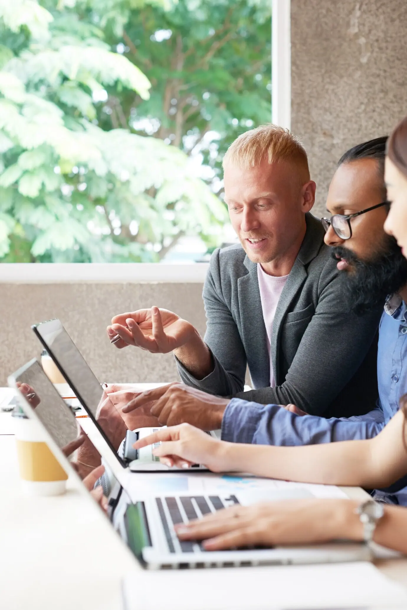 Drei Kollegen arbeiten im Büro an einem Laptop und besprechen etwas.