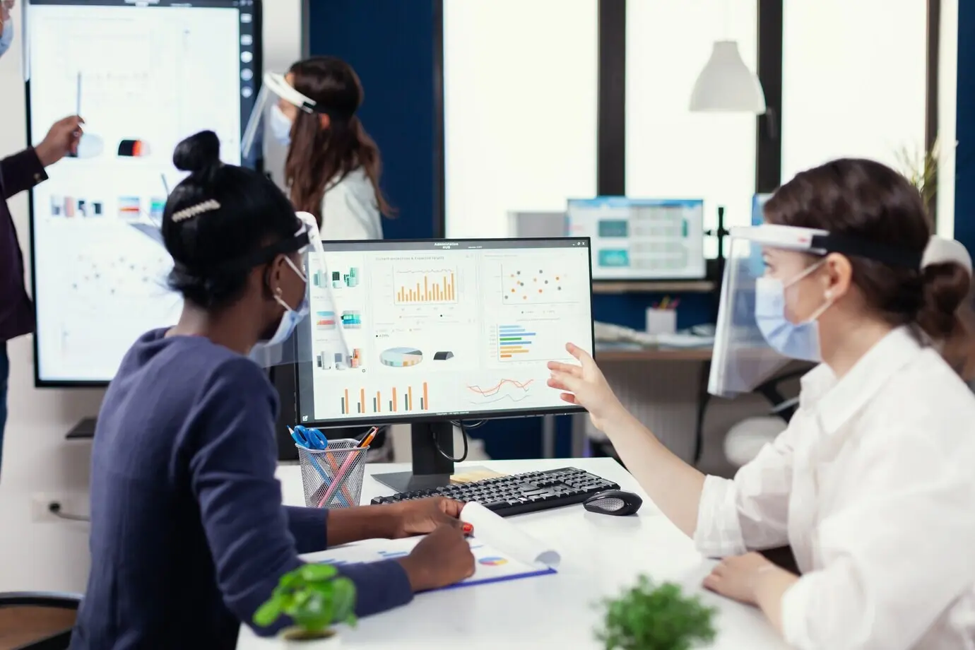 Ein Manager zeigt einem afrikanischen Kunden den jährlichen Finanzbericht und trägt eine Gesichtsmaske gegen COVID-19.